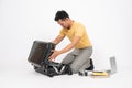 A handsome Asian man is packing his belongings into his travel luggage, isolated white background Royalty Free Stock Photo