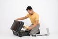 A handsome Asian man is packing his belongings into his travel luggage, isolated white background Royalty Free Stock Photo