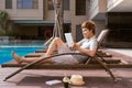 Handsome asian man relaxing by pool and reading e-book Royalty Free Stock Photo