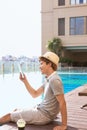 Handsome asian man relaxing by pool and reading e-book Royalty Free Stock Photo