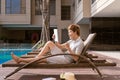 Handsome asian man relaxing by pool and reading e-book Royalty Free Stock Photo