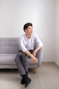 Handsome Asian man sitting at home on sofa, smiling happy Royalty Free Stock Photo