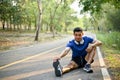 Handsome Asian man in sportswear is stretching his leg on the street at a park Royalty Free Stock Photo