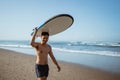 Handsome Asian man with surfboard on his head walking along the beach Royalty Free Stock Photo