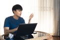 Handsome asian man working on laptop computer in the room looking crumpled paper on hand, Concept of Work from home. Royalty Free Stock Photo