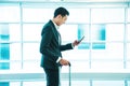 Handsome asian many using smartphone while walking with suitcase at airport terminal. Royalty Free Stock Photo