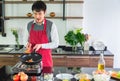 Handsome, Asian young man Smiling happiness.  Frying sausages in a pan for  food Royalty Free Stock Photo