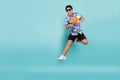 Handsome Asian young man in summer clothes is jumping and using a water gun on a blue background. Songkran Festival in Thailand Royalty Free Stock Photo