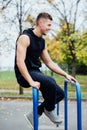 Handsome athlete resting on the bars between sets .