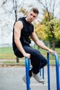 Handsome athlete resting on the bars between sets .