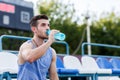 Handsome athletic man drinking water at sports stadium Royalty Free Stock Photo