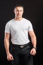 Handsome Athletic man in white blank t-shirt standing on black wall background Royalty Free Stock Photo