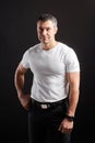 Handsome Athletic man in white blank t-shirt standing on black wall background Royalty Free Stock Photo