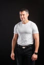 Handsome Athletic man in white blank t-shirt standing on black wall background Royalty Free Stock Photo