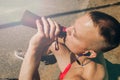 Handsome athletic runner seated on the steps drink water, beautiful fit man in bright fluorescent sportswear Royalty Free Stock Photo