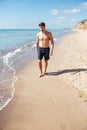 Handsome athletic young man walking along the beach Royalty Free Stock Photo