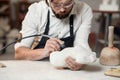 Attentive stonemason with stylish beard in protective goggles detailing creative sculpture of woman torso at his Royalty Free Stock Photo