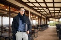 Handsome attractive businessman using a laptop on office terrace. Stylish man in glasses coat and scarf standing on Royalty Free Stock Photo