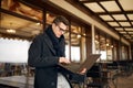 Handsome attractive businessman using a laptop on office terrace. Stylish man in glasses coat and scarf standing on Royalty Free Stock Photo