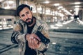 Handsome and attractive guy is standing in an empty hangar. He is alone there. Young man is holding black gun in his Royalty Free Stock Photo