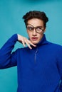 attractive man stands on a light blue background in a blue zip-up sweater with black-rimmed glasses upside down on his Royalty Free Stock Photo