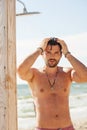 Handsome attractive men with languishing look showering outdoor in beach shower, water drops are falling on his torso Royalty Free Stock Photo