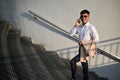 Handsome Asian businessman talking on the phone while walking on the stairs in a city Royalty Free Stock Photo