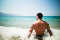 Handsome attractive muscular man sitting on sea shore on the beach sand and relaxing.Handsome man with tattoo sunbathing, spf