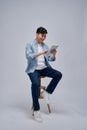 Handsome attractive smiling happy young male using tablet and sitting on the chair Royalty Free Stock Photo