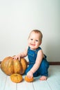 Handsome baby in denim overalls and pumpkin. Complementary feeding of children, first autumn of toddler, Halloween, food allergies Royalty Free Stock Photo