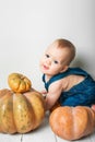 Handsome baby in denim overalls and pumpkin. Complementary feeding of children, first autumn of toddler, Halloween, food allergies Royalty Free Stock Photo