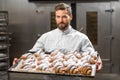 Handsome baker holding tray full of freshly baked croisants Royalty Free Stock Photo