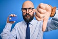 Handsome bald business man with beard holding credit card over isolated blue background with angry face, negative sign showing Royalty Free Stock Photo