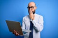 Handsome bald business man with beard working using laptop over blue background cover mouth with hand shocked with shame for Royalty Free Stock Photo