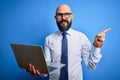 Handsome bald business man with beard working using laptop over blue background very happy pointing with hand and finger to the Royalty Free Stock Photo