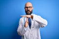 Handsome bald doctor man with beard wearing glasses and stethoscope over blue background Doing time out gesture with hands, Royalty Free Stock Photo