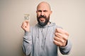 Handsome bald man with beard holding reminder paper with negative message annoyed and frustrated shouting with anger, crazy and