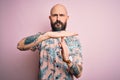 Handsome bald man with beard and tattoo wearing casual floral shirt over pink background Doing time out gesture with hands, Royalty Free Stock Photo