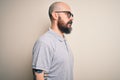 Handsome bald man with beard and tattoo wearing casual polo and glasses looking to side, relax profile pose with natural face with Royalty Free Stock Photo