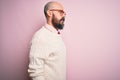 Handsome bald man with beard and tattoo wearing glasses and sweater over pink background looking to side, relax profile pose with Royalty Free Stock Photo