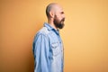 Handsome bald man with beard wearing casual denim jacket and striped t-shirt looking to side, relax profile pose with natural face Royalty Free Stock Photo