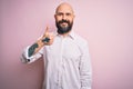 Handsome bald man with beard wearing elegant shirt over isolated pink background doing happy thumbs up gesture with hand Royalty Free Stock Photo