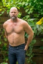 Handsome bald man posing with no shirt in the garden