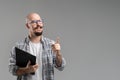 Handsome balded beard with musctache man wearing casual clothes holding clipboard isolated over gray background.