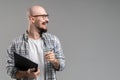 Handsome balded beard with musctache man wearing casual clothes holding clipboard smiling isolated over gray background