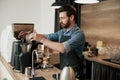 Handsome barista grinds coffee beans in coffeemachine