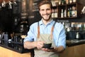 Handsome barista offering a cup of coffee to camera at the coffee shop Royalty Free Stock Photo