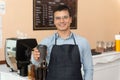 Handsome barista offering a cup of coffee to camera at the coffee shop Royalty Free Stock Photo