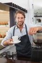 Handsome barista offering a cup of coffee to camera Royalty Free Stock Photo