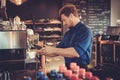 Handsome barista preparing cup of coffee for customer in coffee shop.